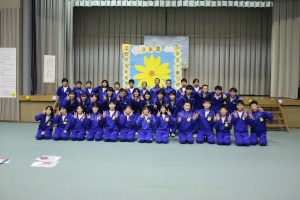 体育館で青いジャージを着た生徒たちが集合して記念撮影をしている写真