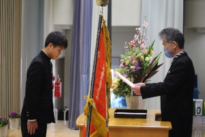 体育館で生徒が卒業証書を受け取っている写真