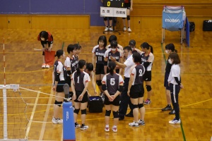 バレーボールの試合中に作戦を確認する選手たちの写真