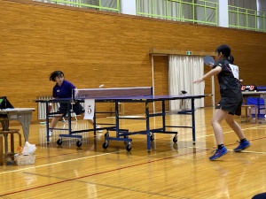 体育館で卓球の試合でラリーをする2人の生徒の写真