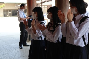 マスクをした3人の女子生徒が手をたたいてお祈りをしている写真