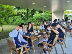 木の机で食事をしながらピースサインをしている生徒たちの写真
