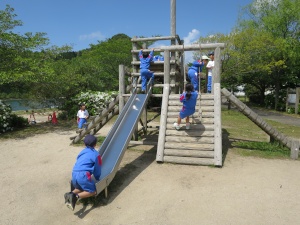 公園にある滑り台や梯子などが組み合わされた大きな遊具で遊ぶ児童たちの写真