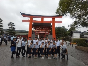 大きな鳥居の前に2列に集合している男女の生徒の写真