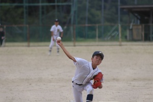 グラウンドで野球のユニフォームを着た生徒が振りかぶっている写真