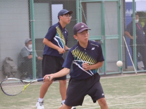 テニスコートで男子生徒が軟式テニスをしている写真