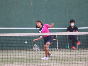 テニスコートで女子生徒が返ってきたテニスボールを打ち返そうとしている写真