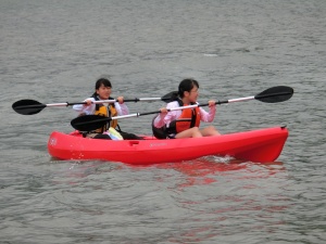 海で女子生徒2人が赤色のカヌーを漕いでいる写真