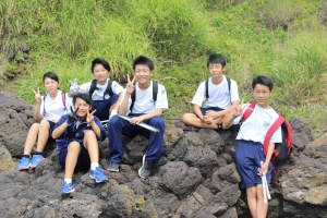 岩場で男子生徒たちが岩に座って記念撮影している写真