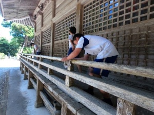 神社の建物の廊下の手すりを拭いている児童の写真