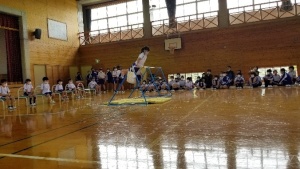 体育館に置かれた鉄棒でパフォーマンスをする児童の写真