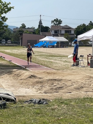 走り幅跳びの砂場に向かって走る女子児童の写真