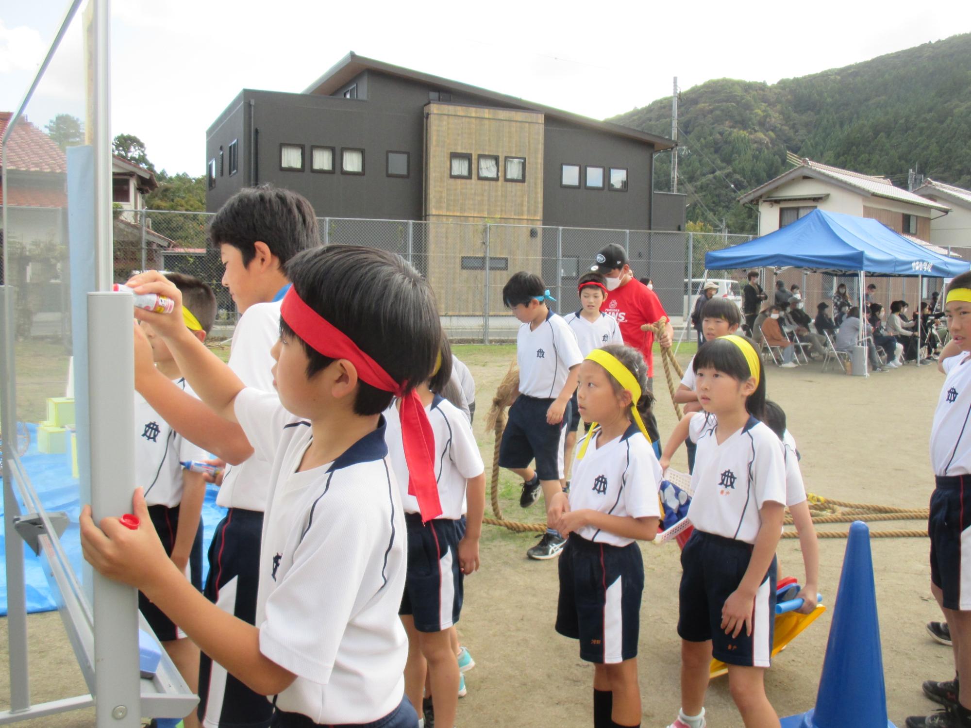 グラウンドでスコアボードに得点を記入する児童たちの写真