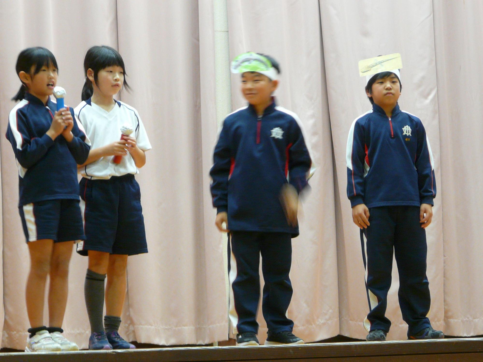 舞台上でマイクを持って発表している児童たちの写真