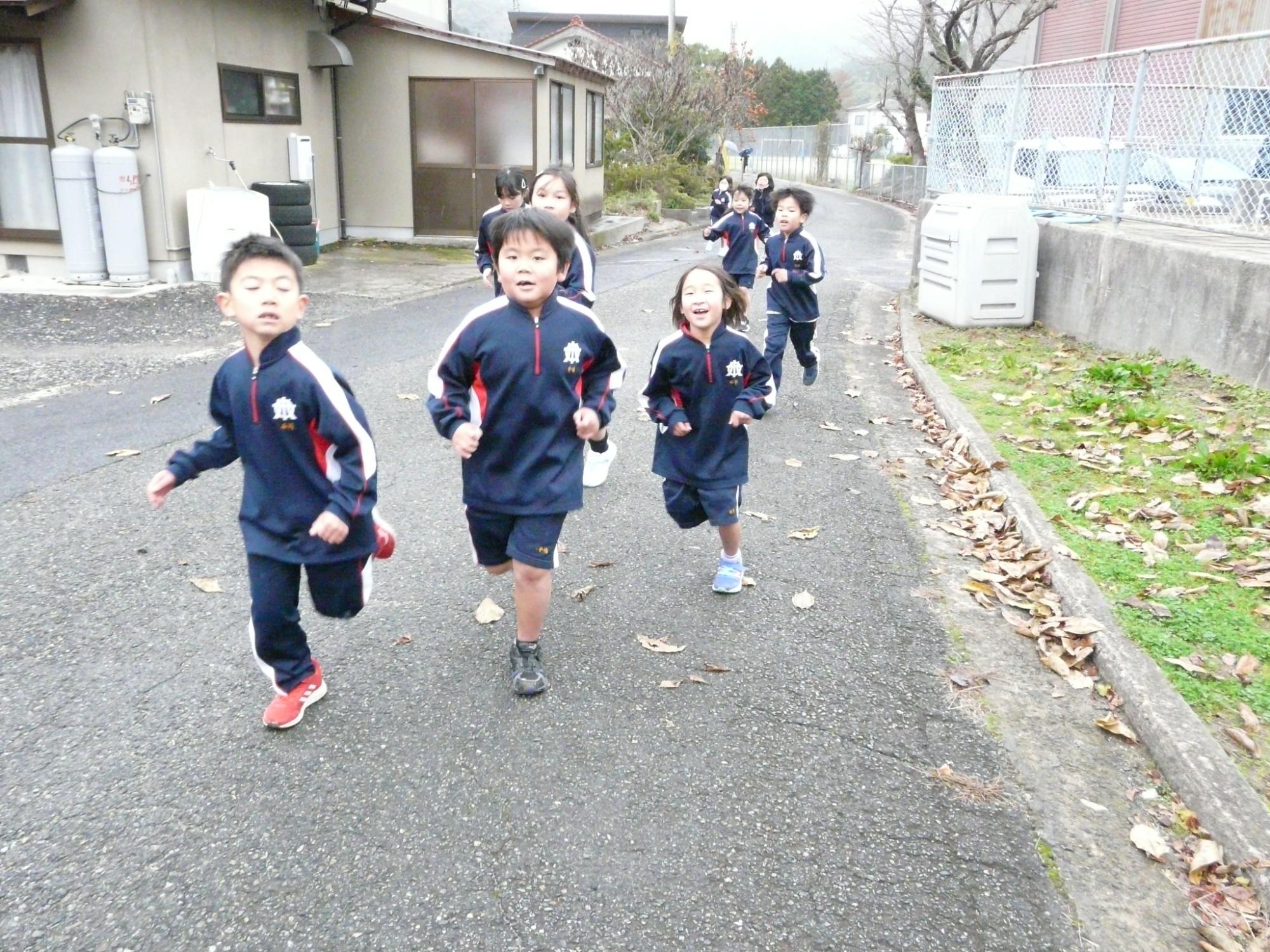校舎の前の道を元気に走る児童たちの写真
