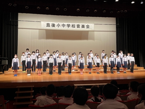 舞台上で整列をして合唱をしている児童たちの写真