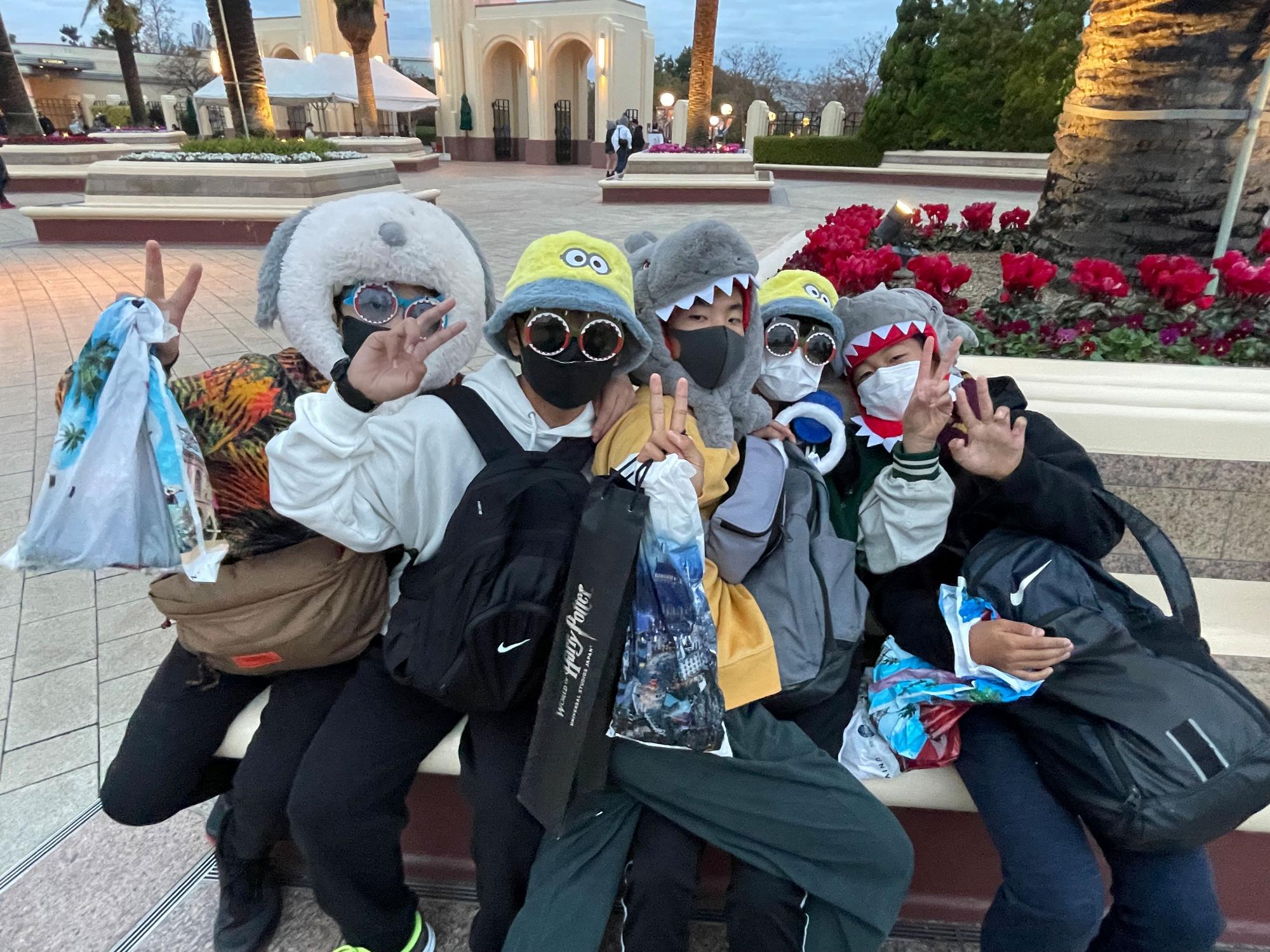 キャラクターの帽子やサングラスをかけてピースをしている生徒たちの写真