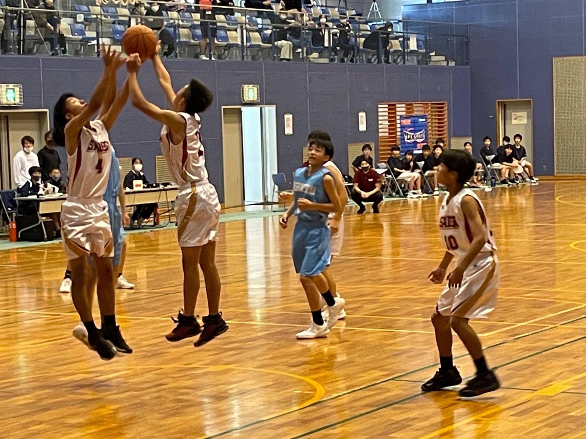 体育館で降ってきたバスケットボールを取り合う生徒たちの写真