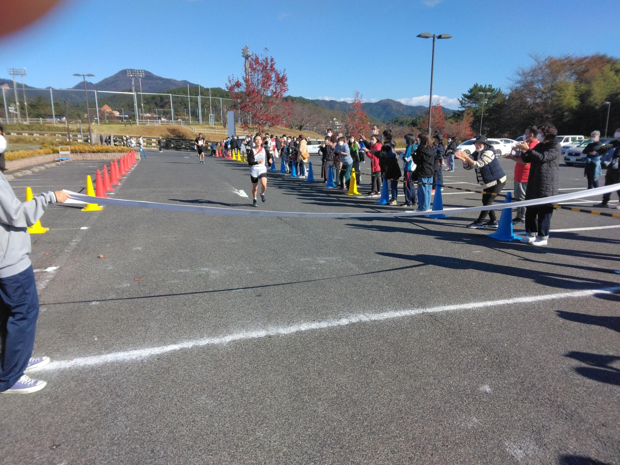 ゴールテープに向かって走ってくる生徒と後ろを追う生徒の写真