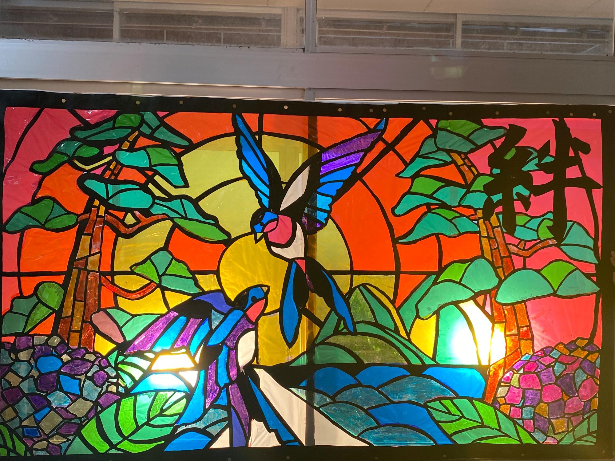 2羽の鳥が描かれ絆と文字が入っているステンドグラスの写真