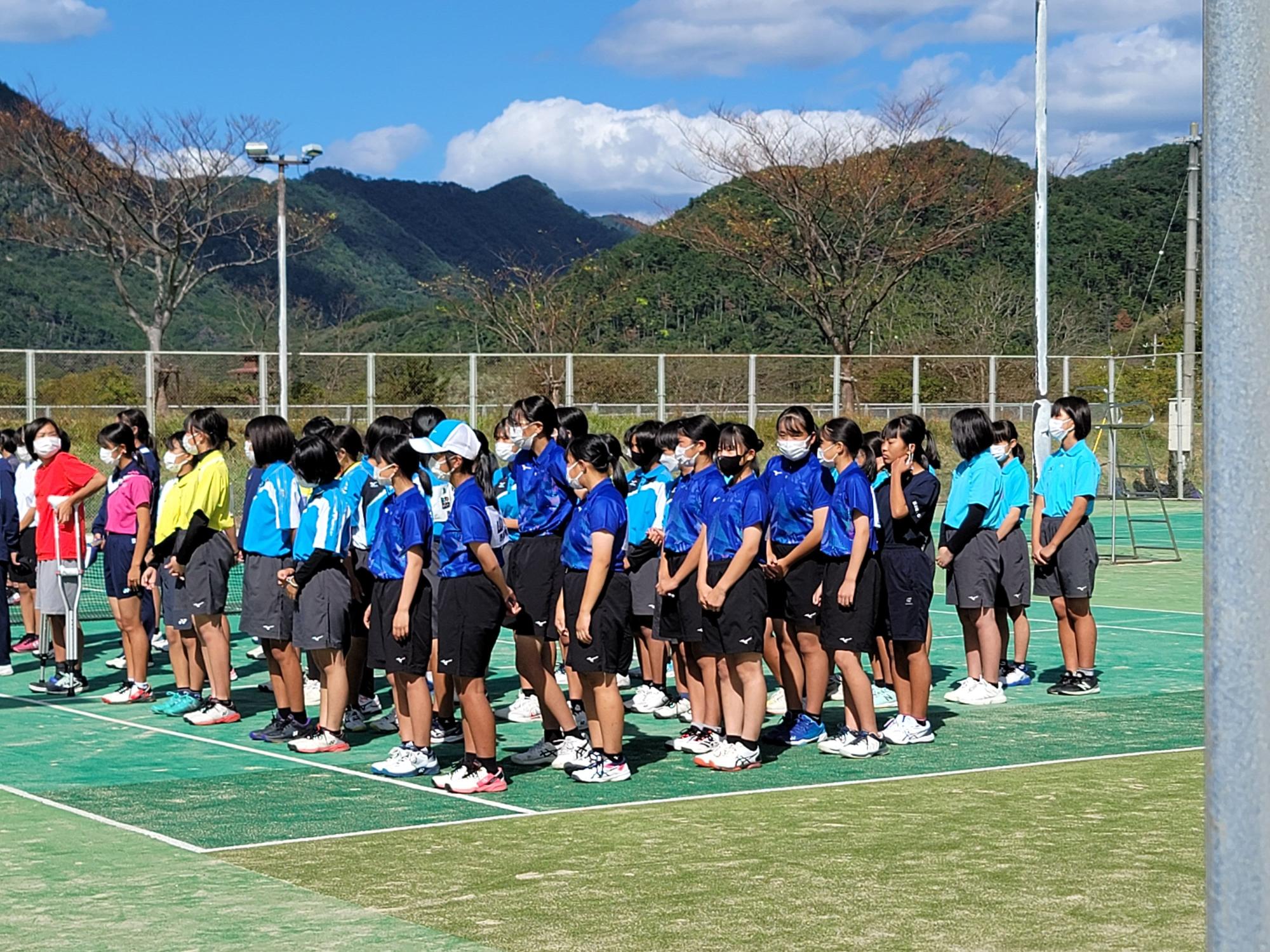 テニスコートで整列する生徒たちの写真