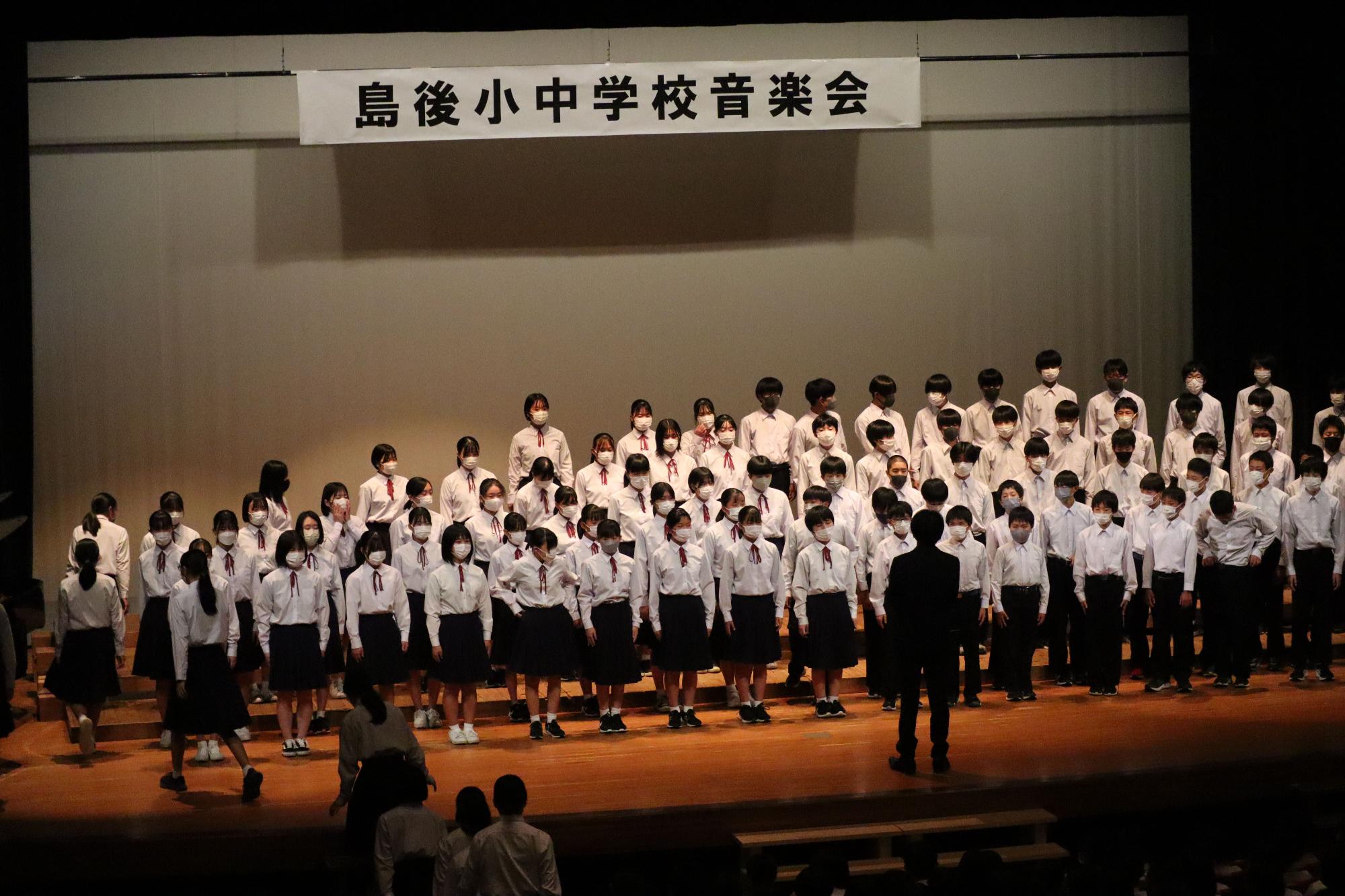 舞台上で整列して歌う生徒たちの写真