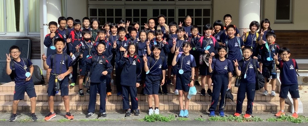 校舎前の階段でジャージを着た児童たちが整列して記念撮影をしている写真