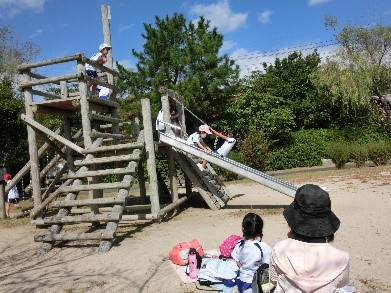 公園の遊具のすべり台で児童が滑って遊んでいる写真