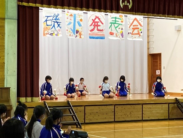 体育館の舞台で児童たちが発表会の演目を披露している写真