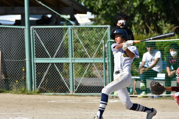 グラウンドで生徒が野球の試合でスイングをしている写真