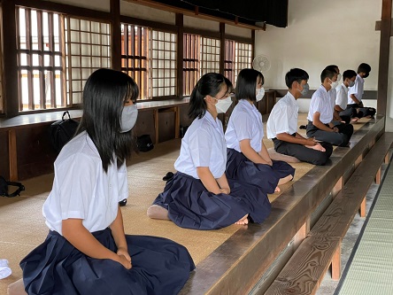 寺院で生徒たちが正座をして座禅体験をしている写真