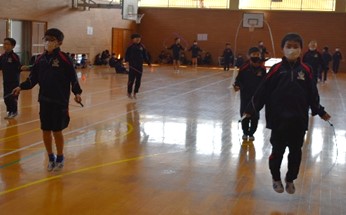 体育館で児童たちが縄跳びをしている様子の写真