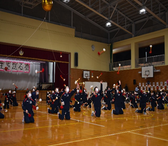 体育館で児童たちが整列して出し物を披露している様子の写真