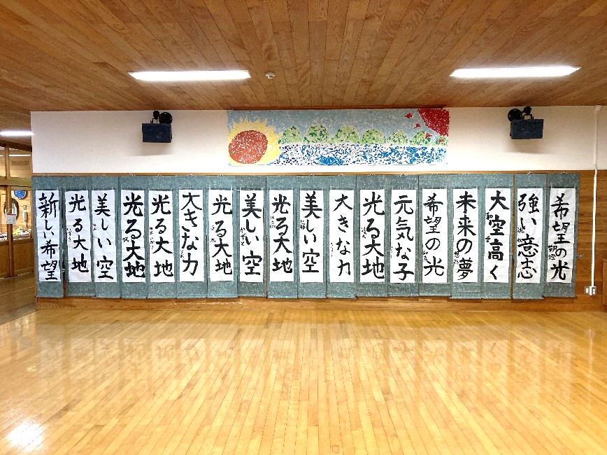 校舎内で児童の書き初め作品が壁一面に並べられている写真