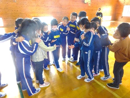 体育館でたくさんの児童たちが円になって遊んでいる写真