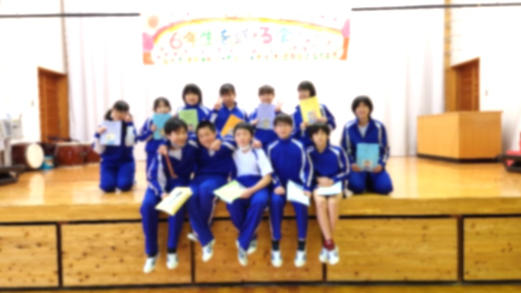体育館のステージ上で児童たちが記念写真を撮っている写真