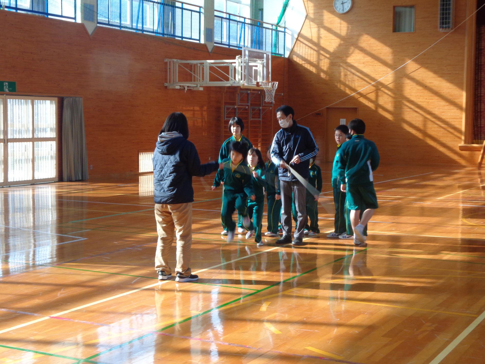 体育館で児童たちが大縄跳びの練習をしている写真