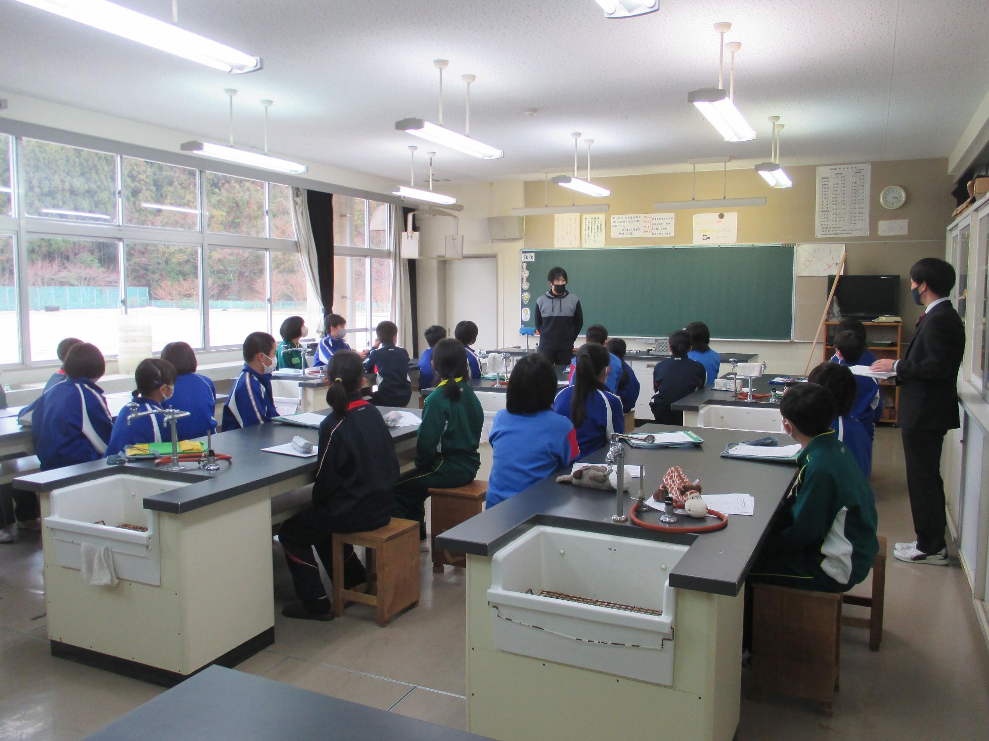 理科室で生徒たちが先生の授業を聞いている写真