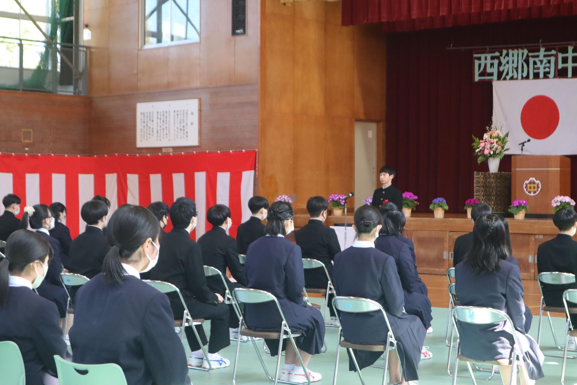 体育館で在校生代表が卒業式で送辞を述べている写真