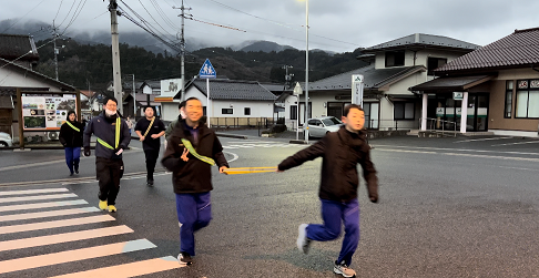 町中の交差点を生徒たちが走っている写真
