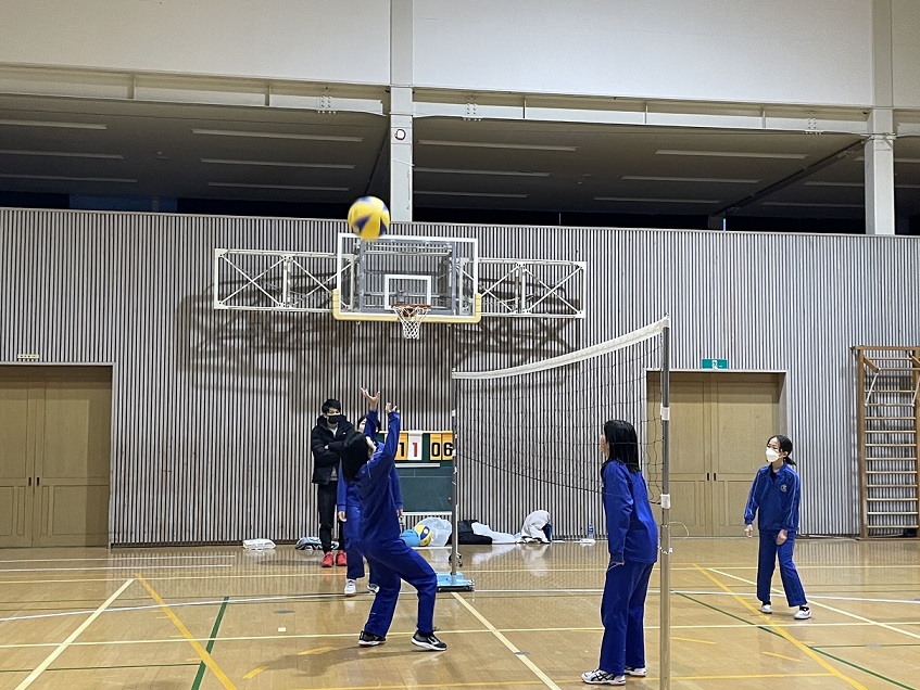 体育館で女子生徒たちがバレーボールをしている写真