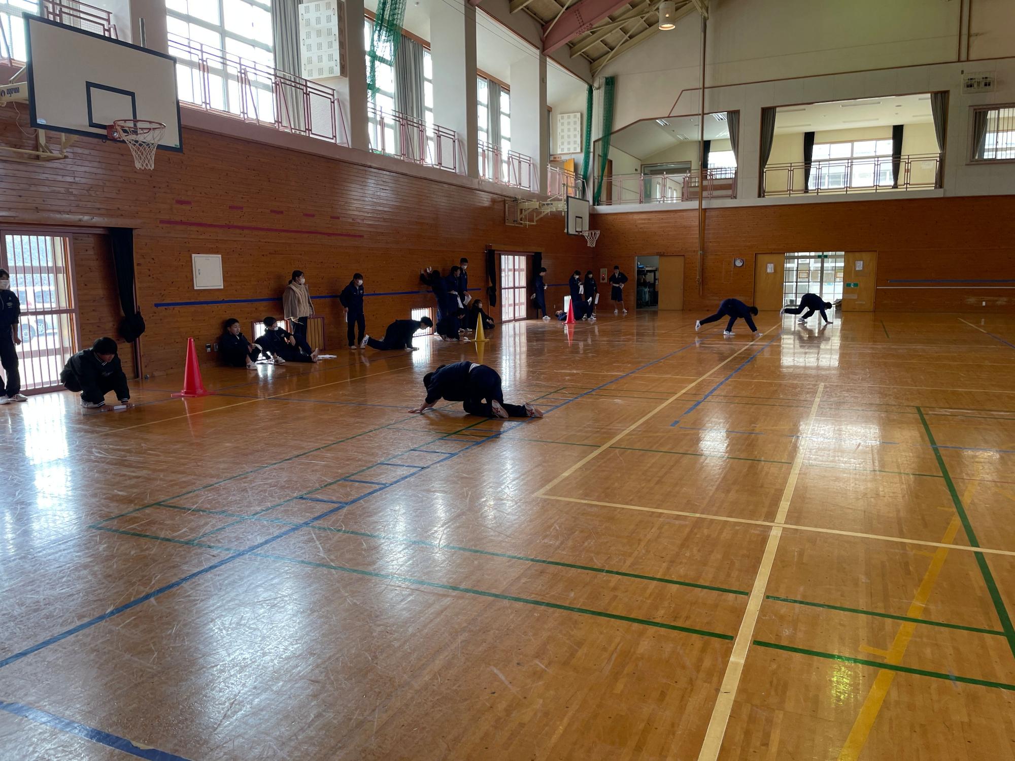 体育館でジャージを着た生徒たちが雑巾がけをしている写真