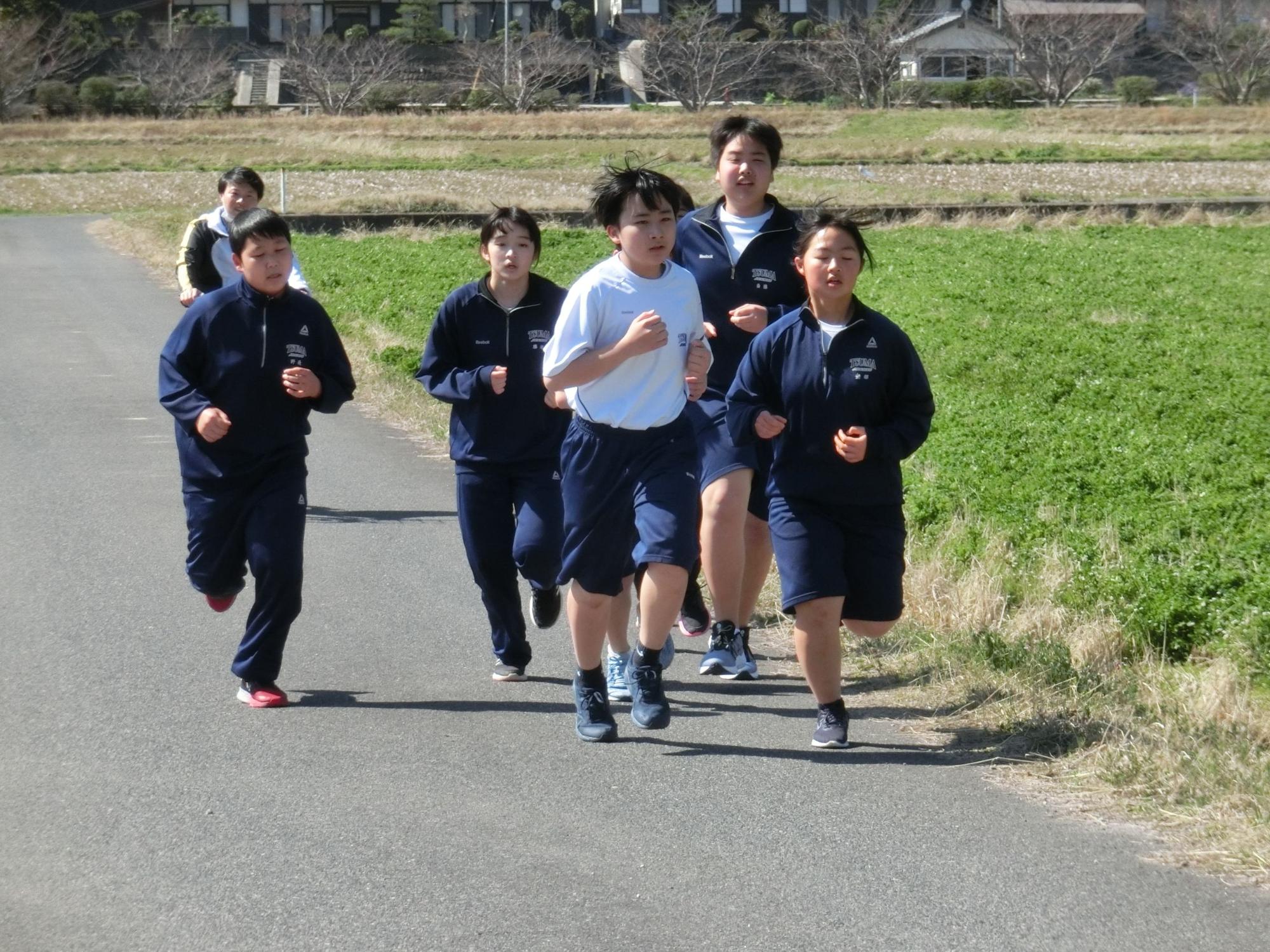 校外の道で生徒たちが集団でマラソン大会を走っている写真