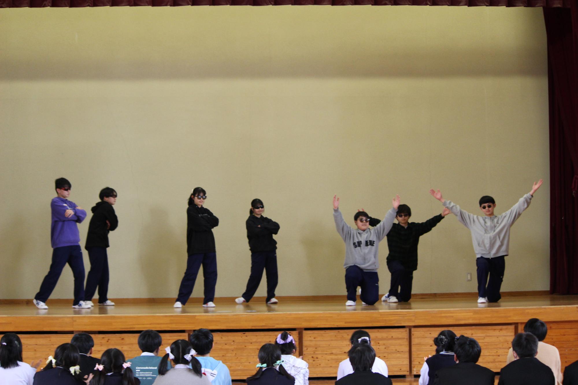 体育館の舞台で生徒たちがダンスを発表している写真