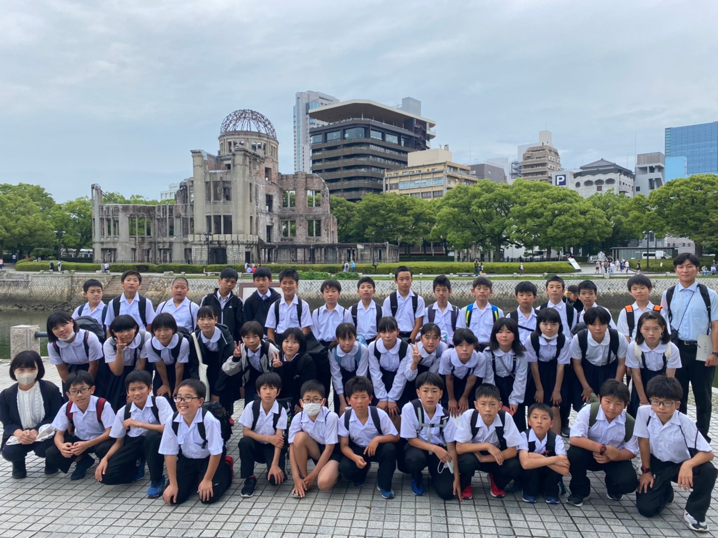 修学旅行で原爆ドーム前で集合写真を撮る児童の写真