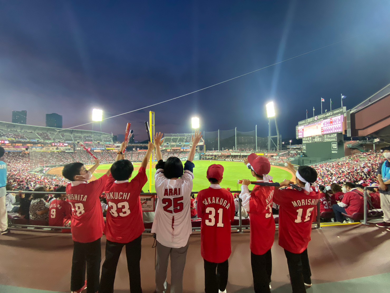 野球観戦でカープを応援する児童の写真