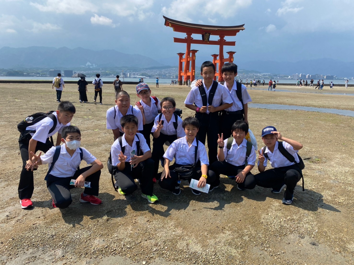 宮島の大鳥居前で集合写真を撮る児童の写真