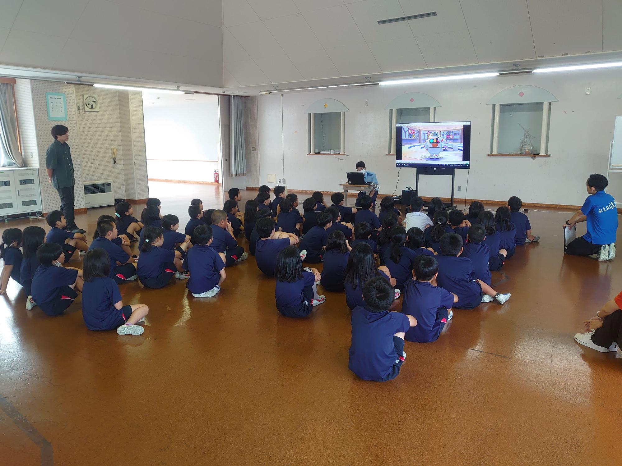 教室でモニター映像を見ながら学習する児童の写真