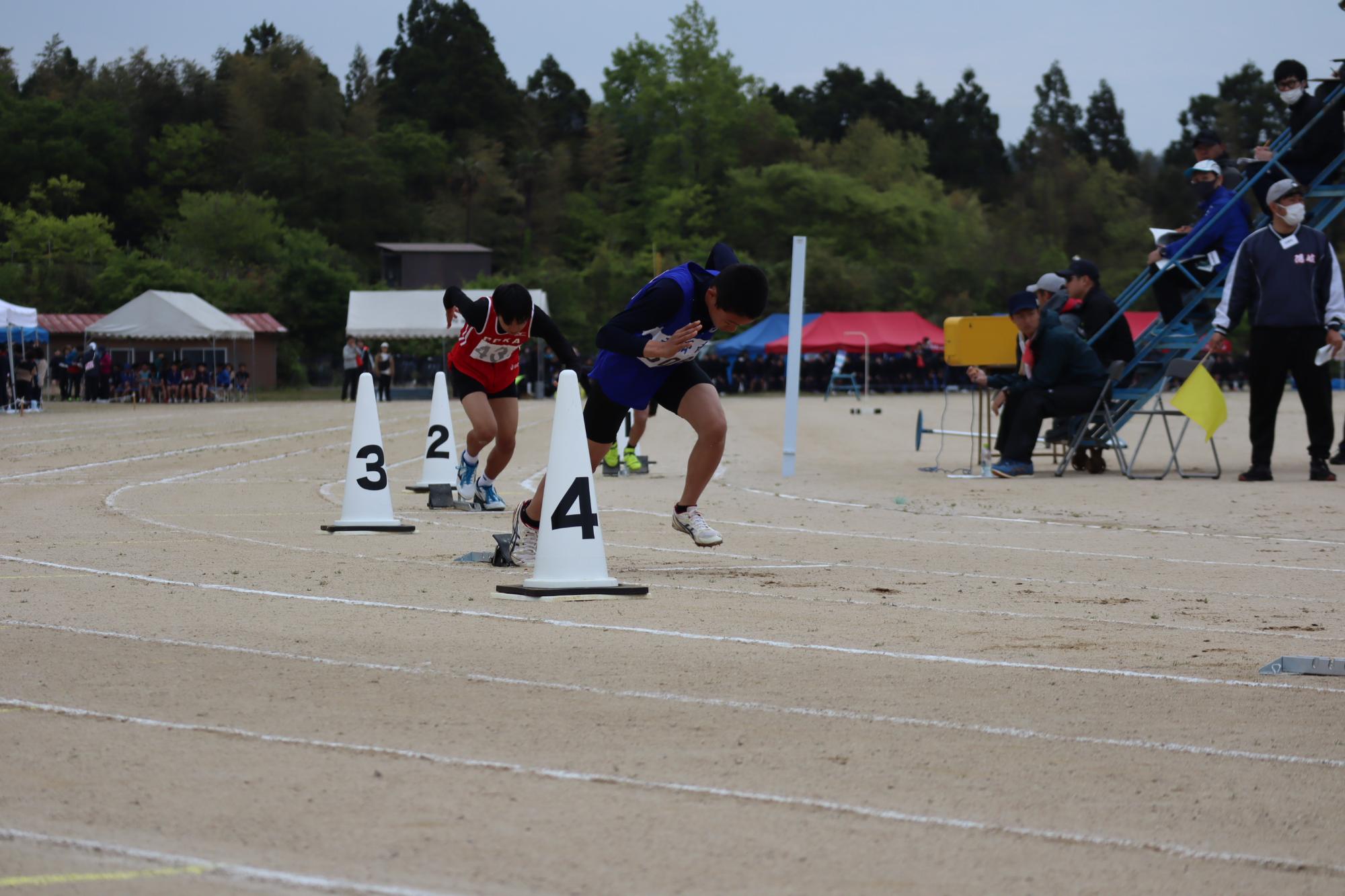 陸上競技大会で生徒二名がトラックを走っている写真