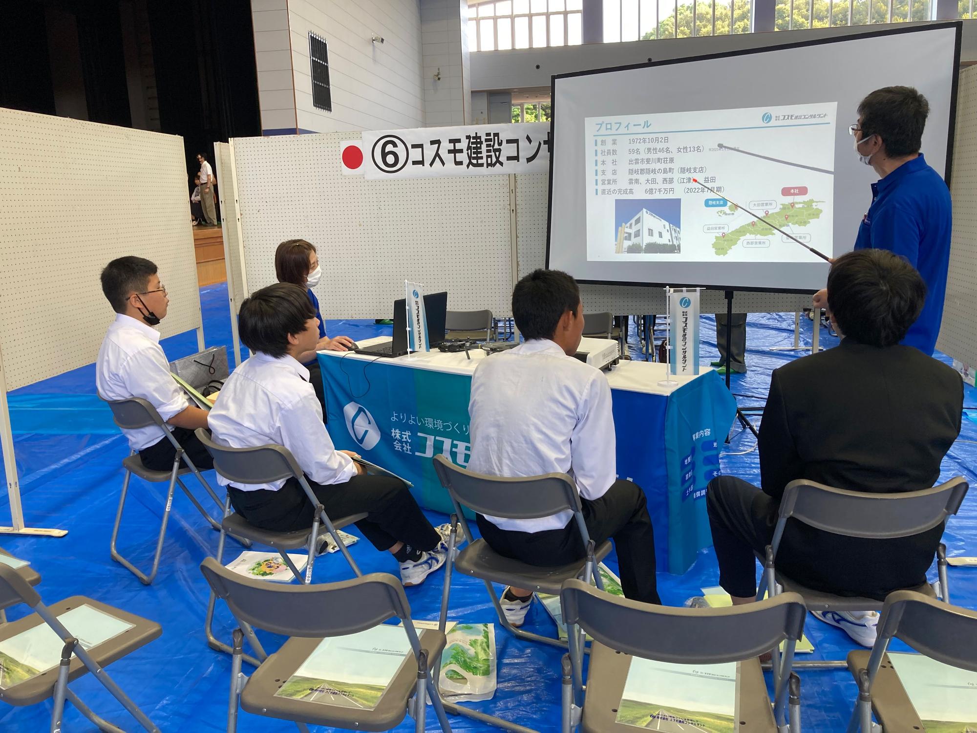 企業説明会で生徒たちが担当者の話を聞いている写真